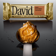 David Salted Peanut Butter flavored protein bar with a spoonful of peanut butter on a dark background.