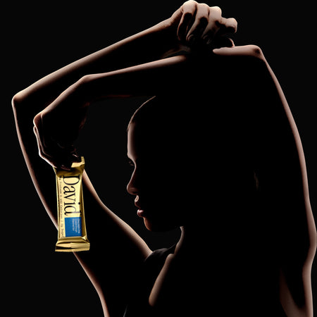 Silhouette of a person holding a chocolate bar with 'David' branding against a black background