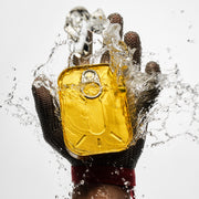 Hand wearing a silver glove holding a yellow fish can with water splashing