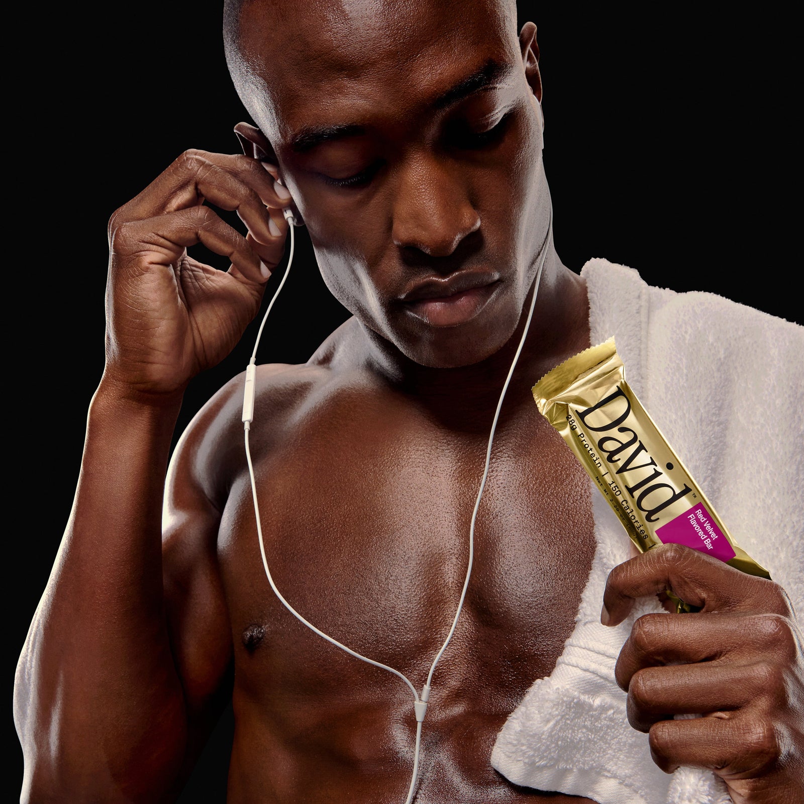 Man listening to music with earphones and holding a David protein bar.
