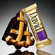 David Blueberry Pie flavored protein bar with a slice of blueberry pie on a gray background