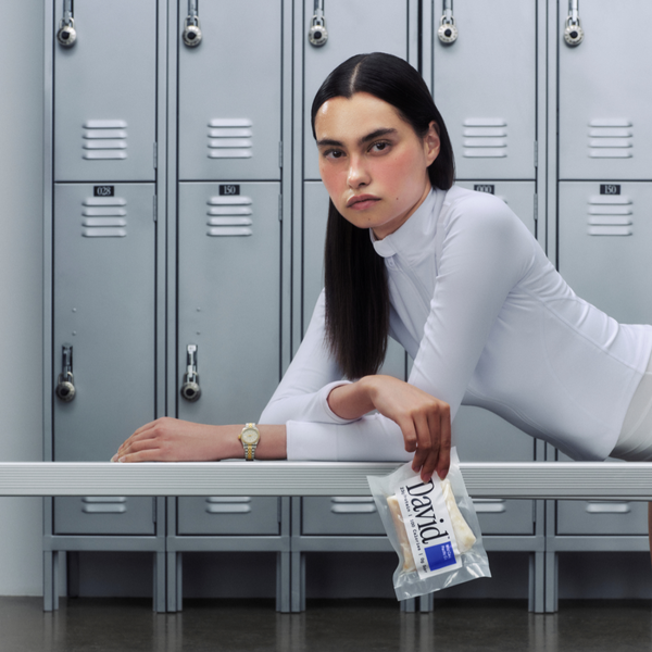 Person in a white outfit holding a package of David Cod in front of gray lockers