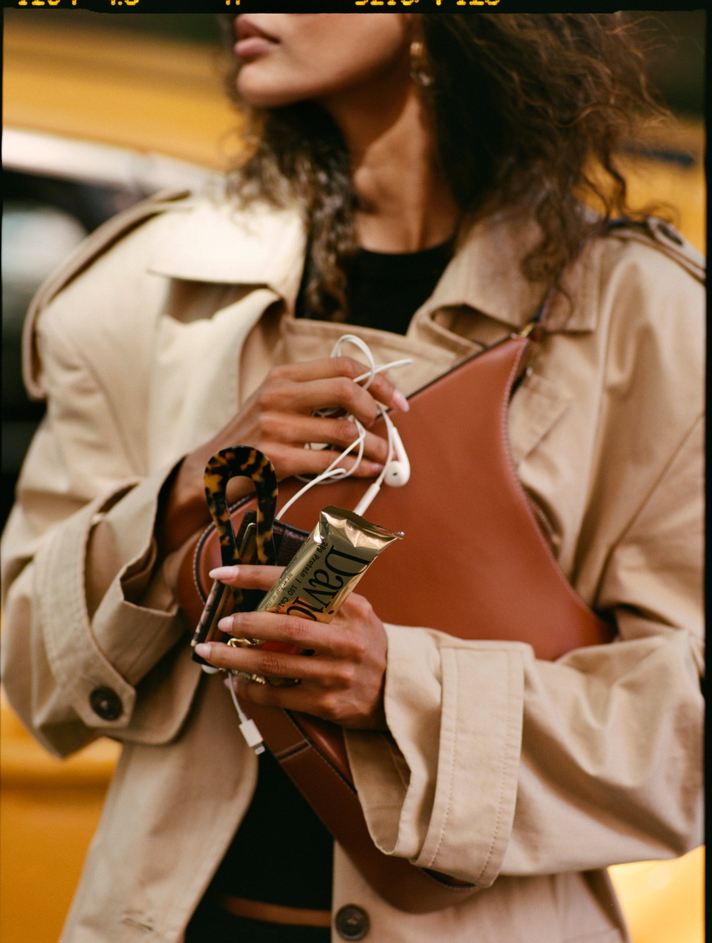 Person holding a David Protein bar in an outdoor New York setting, candid lifestyle image with urban backdrop.