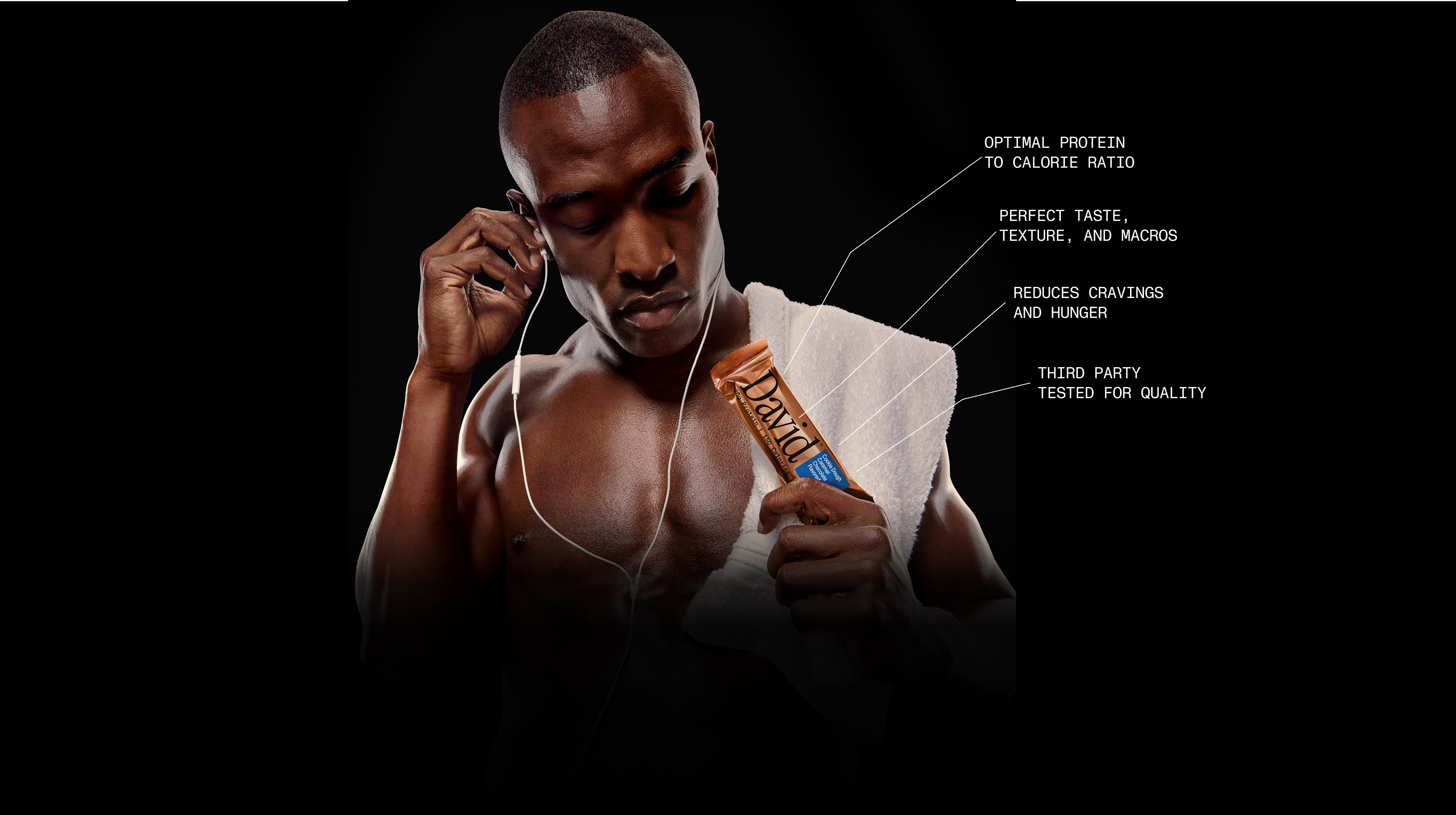 Man wearing earphones with a towel over his shoulder holding a David Bronze protein bar, with text callouts stating optimal protein to calorie ratio, perfect taste, texture and macros, reduces cravings and hunger, and third party tested for quality.