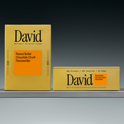 Two boxes of David Peanut Butter Chocolate Chunk Flavored Bars on a shelf with a gray background.