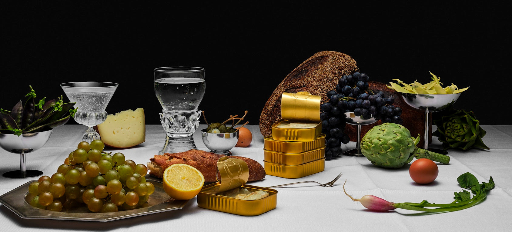 Table setting with fruits, vegetables, and gold bars against a dark background