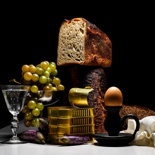 Still life with bread, grapes, and cod on a dark background