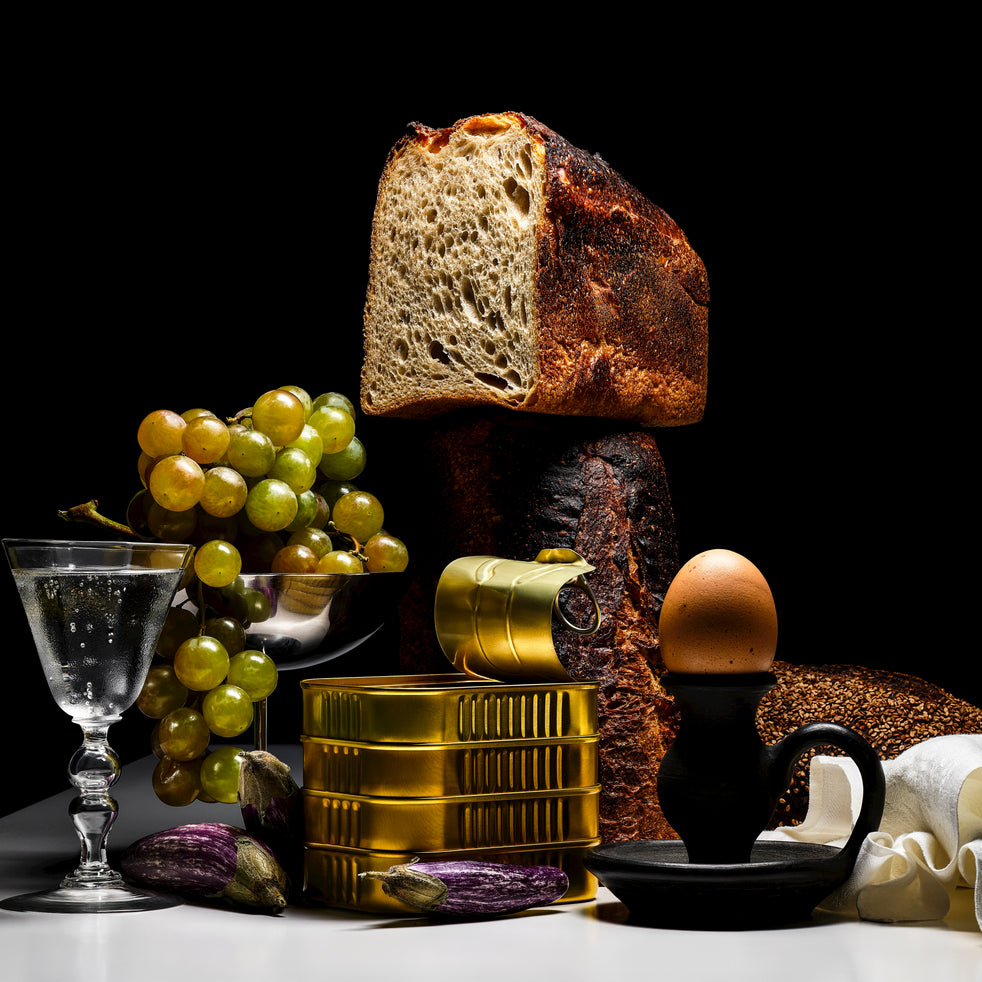 Still life with bread, grapes, and cod on a dark background
