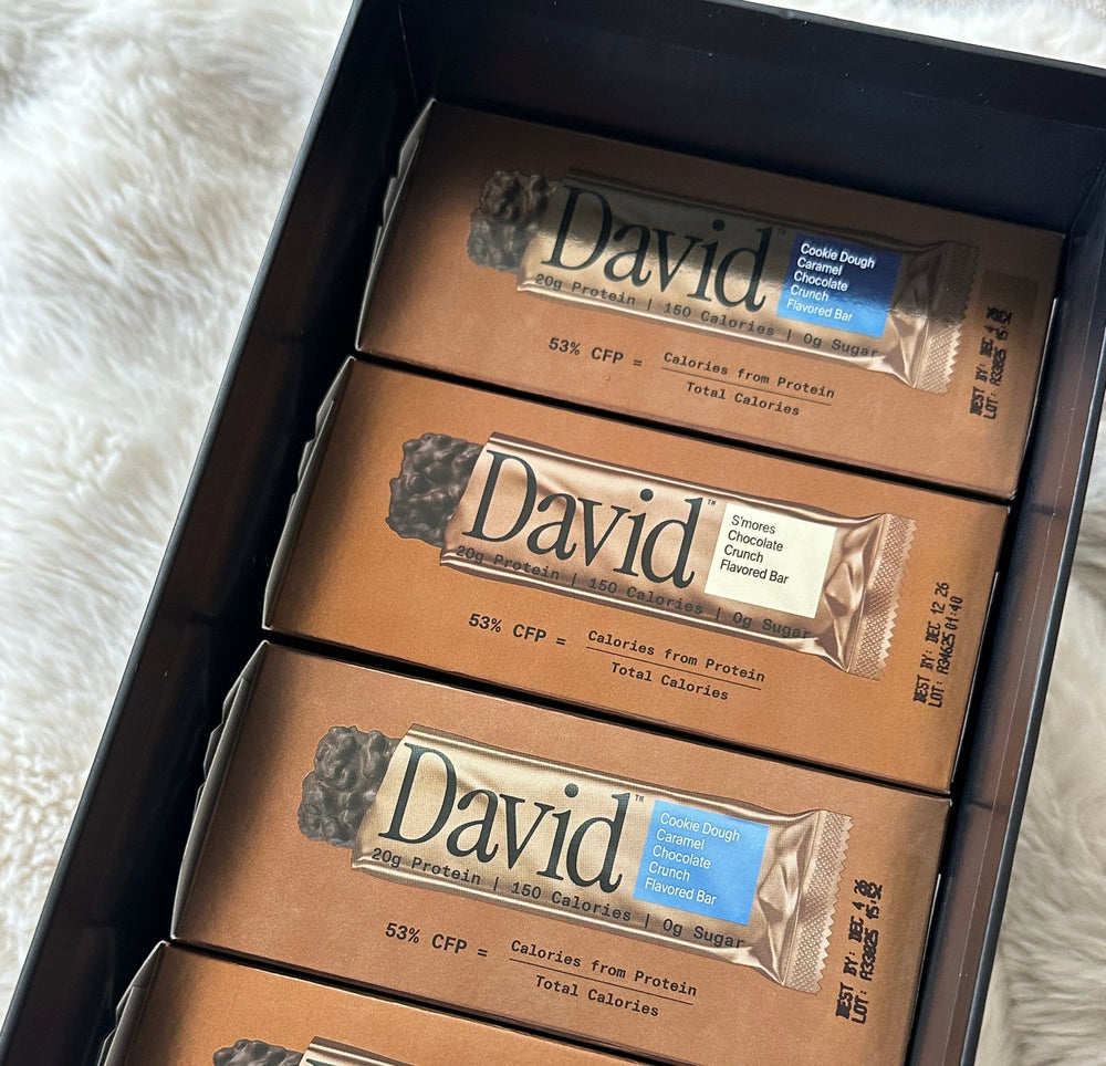 Boxes of S'mores Chocolate Crunch and Cookie Dough Caramel Crunch protein bars on a white background