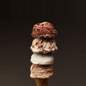 Frozen dessert cone with three scoops of different flavors on a dark background
